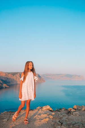 Little girl on top of a mountain enjoying valley view before sunsetの写真素材