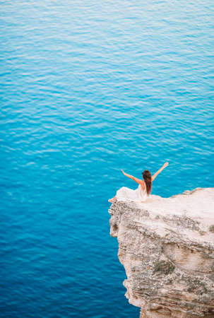 Tourist woman outdoor on edge of cliff seashoreの写真素材