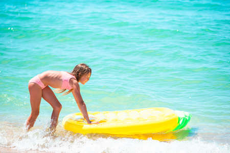 Adorable girl on inflatable air mattress in the seaの写真素材