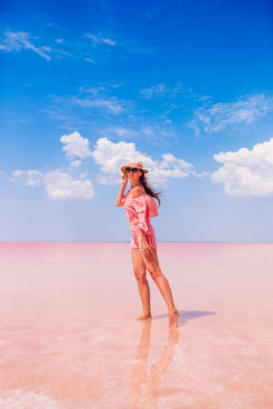 Woman in hat walk on a pink salt lake on a sunny summer day.の写真素材