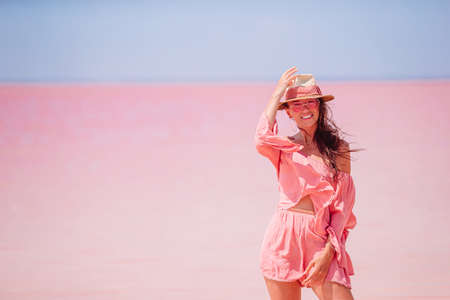 Woman in hat walk on a pink salt lake on a sunny summer day.の写真素材