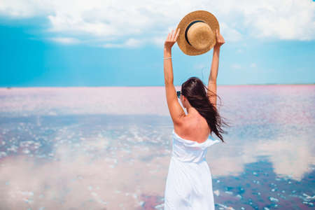 Woman in hat walk on a pink salt lake on a sunny summer day.の写真素材