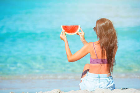 Happy girl having fun on the beach and eating watermelonの写真素材
