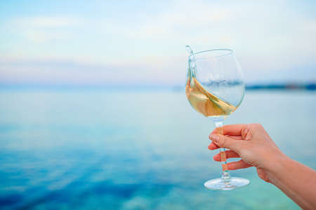 Glass of white wine on tropical beachの写真素材