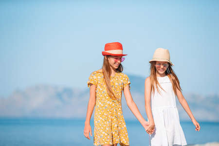 Little happy funny girls have a lot of fun at tropical beach playing together.の写真素材