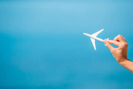 Small white miniature of an airplane on background of blue sky