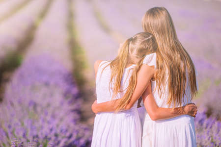 Girls in lavender flowers field at sunset in white dressの写真素材