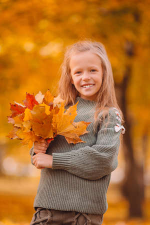 Portrait of adorable little girl with yellow leaves bouquet in fallの写真素材
