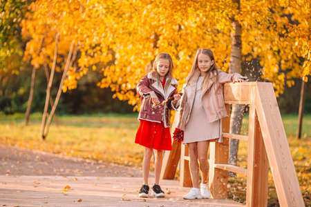 Little adorable girls at warm sunny autumn day outdoorsの写真素材