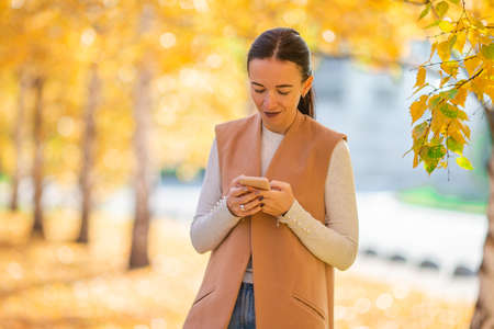 Fall concept - beautiful woman in autumn park under fall foliageの写真素材