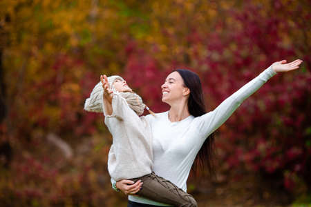 Little girl with mom outdoors in park at autumn dayの写真素材
