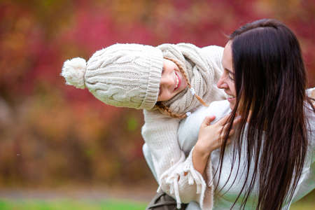 Little girl with mom outdoors in park at autumn dayの写真素材