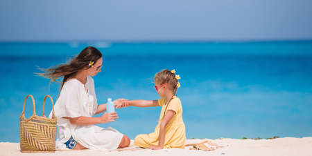 Young mother applying sun cream to daughter nose on the beach. Sun protectionの写真素材