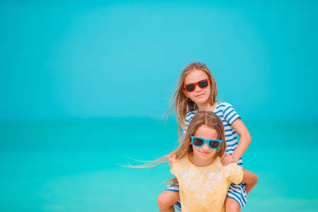 Two little happy girls have a lot of fun at tropical beach playing together