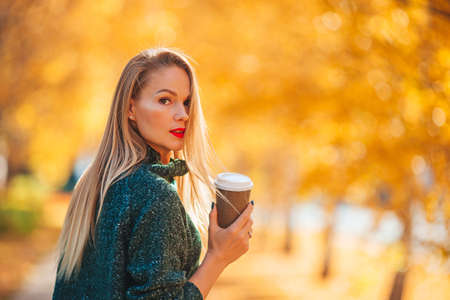 Fall concept - beautiful woman in autumn park under fall foliageの写真素材