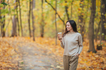 Fall concept - beautiful woman in autumn park under fall foliageの写真素材