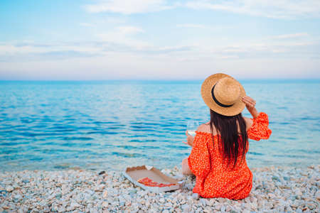 Woman having a picnic with pizza on the beachの写真素材