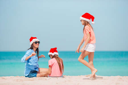 Adorable little girls and young mother on tropical white beachの写真素材
