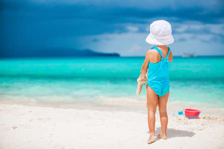 Adorable little girl playing with beach toys on white tropial beachの写真素材