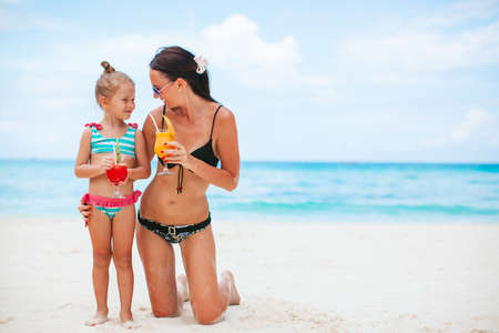 Adorable little girl and young mother on tropical white beachの写真素材