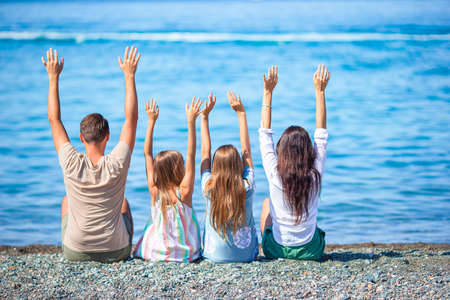 Family of four have fun together on the beach vacationの写真素材