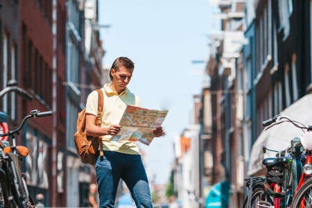 Happy young man with a city map in european cityの写真素材