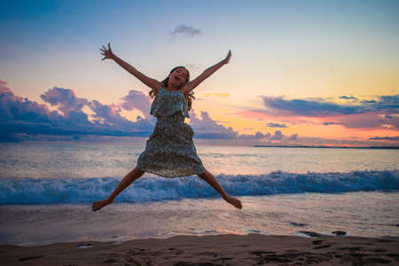 Little happy funny girl have a lot of fun at tropical beach playing togetherの写真素材