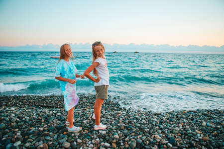 Little happy funny girls have a lot of fun at tropical beach playing togetherの写真素材