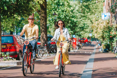Young happy caucasian couple on bikes in old streets in Amsterdamの写真素材
