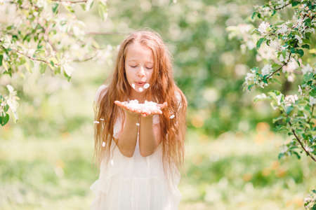 Adorable little girl in blooming apple garden on beautiful spring dayの写真素材