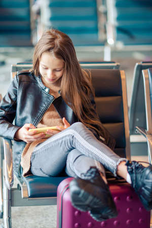 Adorable little girl at airport in big international airport near windowの写真素材