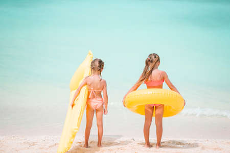 Little happy funny girls have a lot of fun at tropical beach playing together. Sunny day with rain in the seaの写真素材