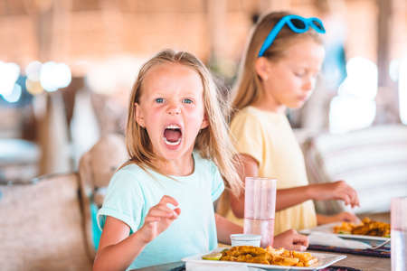 Adorable little girl having breakfast at outdoor cafeの写真素材