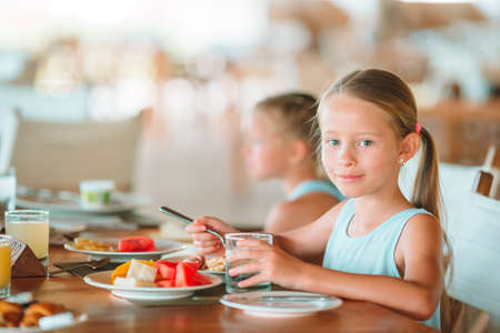 Adorable little girl having breakfast at outdoor cafeの写真素材