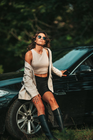 Young woman outdoors standing by her black carの写真素材