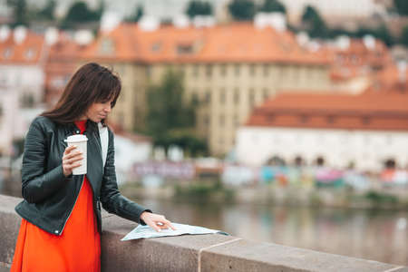 Happy young woman with a city map in city. Travel tourist woman with map outdoors during holidays in Europe.の写真素材