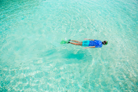 Young man snorkeling in clear tropical turquoise waters