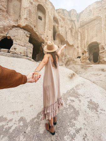 Happy young woman on background of ancient cave formations in Cappadocia following by the man. The Monastery is one of the largest religious buildings.の写真素材