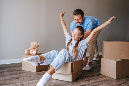 Family of father and adorable teen daughter have fun on moving day in their new homeの写真素材