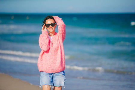 Young happy woman in cold windy weather on the beachの写真素材