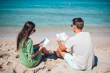 Young couple reading books on tropical beachの写真素材