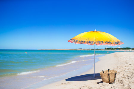 Beach umbrella with straw bag on the tropical beach