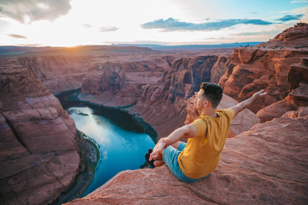 Happy man on the edge of the cliff. Horseshoe Bend Canyon in Page, Arizona. Adventure and tourism conceptの写真素材