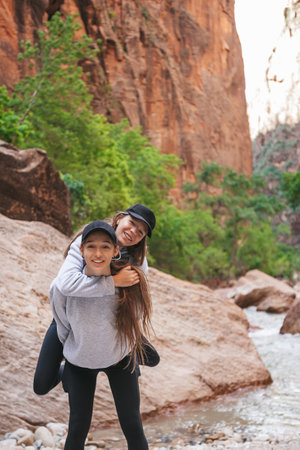 Two girls hiking in the mountains. Teenage girls having fun and walking on pathway in Zion National Park, Utah, USAの写真素材