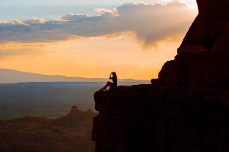 Young hiker woman on the edge of a cliff at Cathedral Rock in Sedona, Arizona. View from Scenic Cathedral Rock in Sedona with blue sky in Arizonaの写真素材