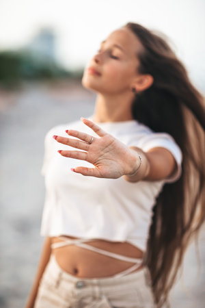 Adorable young girl with beautiful long hair enjoy tropical beach vacation. The girl on the seashore at sunsetの写真素材