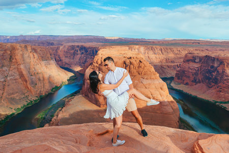 Happy couple on the edge of the cliff at Horseshoe Band Canyon in Paje, Arizona. Adventure and tourism concept. Beautiful nature in USAの写真素材