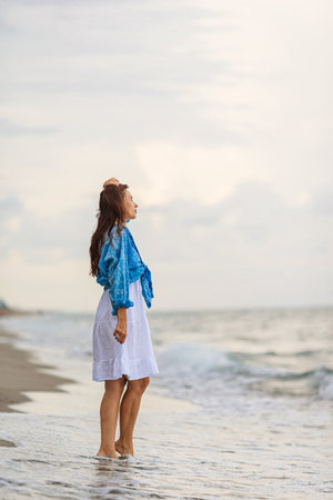 Happy woman enjoying beautiful sunset on the beachの写真素材