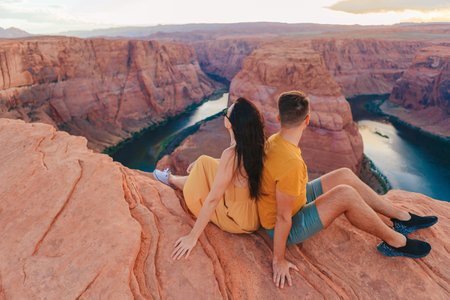 Happy couple on the edge of the cliff at Horseshoe Band Canyon in Page, Arizona. Adventure and tourism concept. Beautiful nature in USAの写真素材