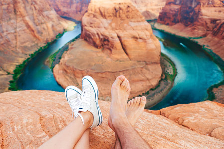 Happy couple on the edge of the cliff at Horseshoe Band Canyon in Page, Arizona. Adventure and tourism concept. Beautiful nature in USAの写真素材